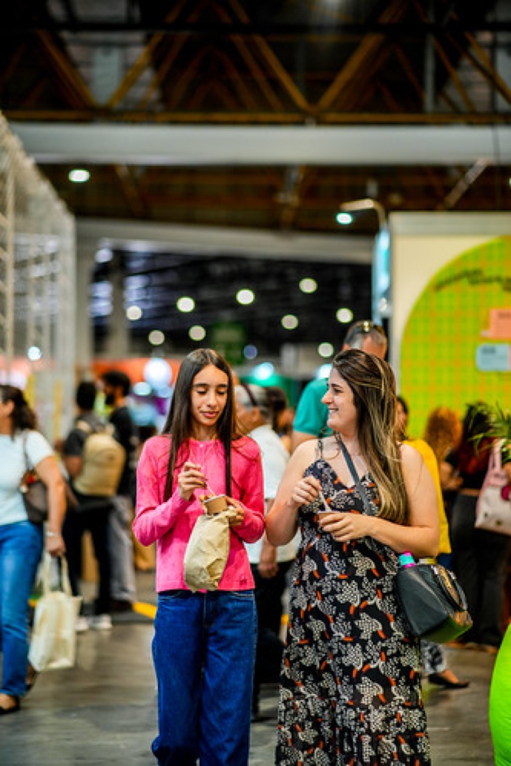 Visitantes conversam e circulam entre os estandes da feira